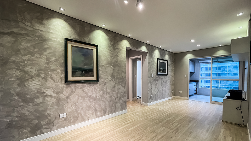 Sala de estar moderna com piso vinílico e acesso à sacada gourmet – Apartamento frente ao mar em Mongaguá