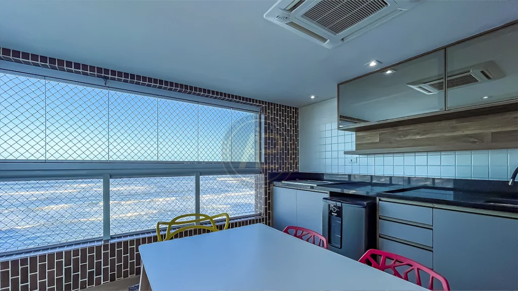 Sacada gourmet mobiliada com armários planejados, mesa e vista para o mar em apartamento de alto padrão em Mongaguá