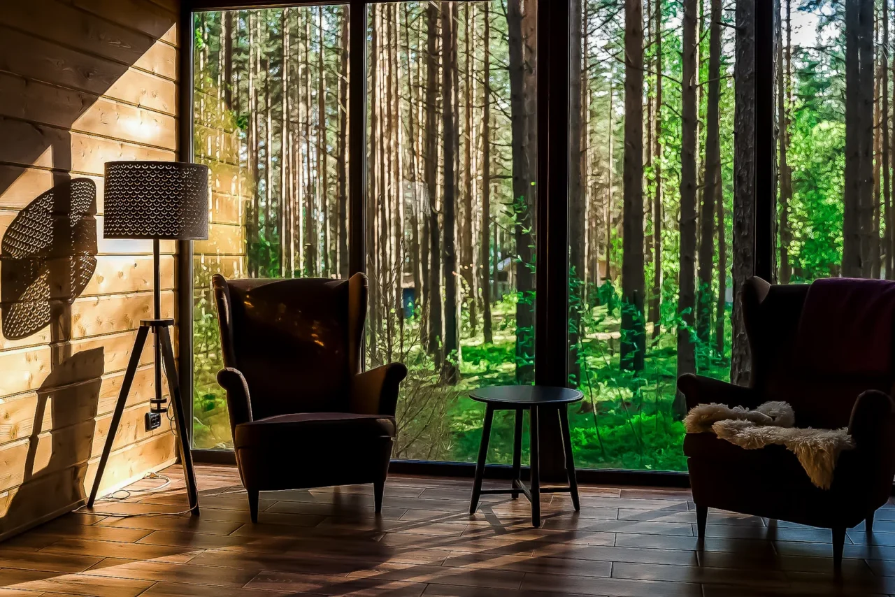 Sala de estar com poltronas e parede de vidro com vista para a natureza — conceito de wellness imobiliário