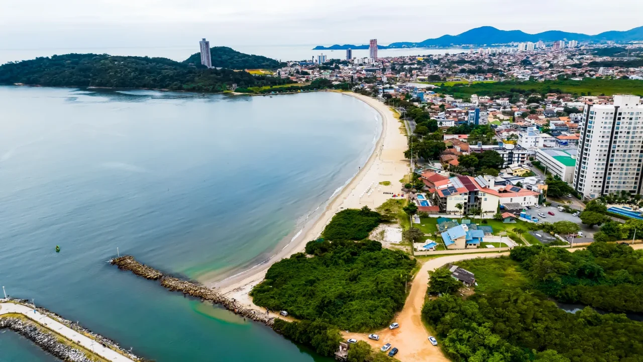 Vista aérea do litoral de São Paulo, com praia, mar e área urbana — região com potencial de valorização em wellness imobiliário