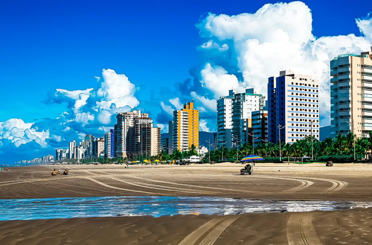 Skyline de prédios residenciais na orla de Mongaguá, com faixa de areia e calçadão ao fundo