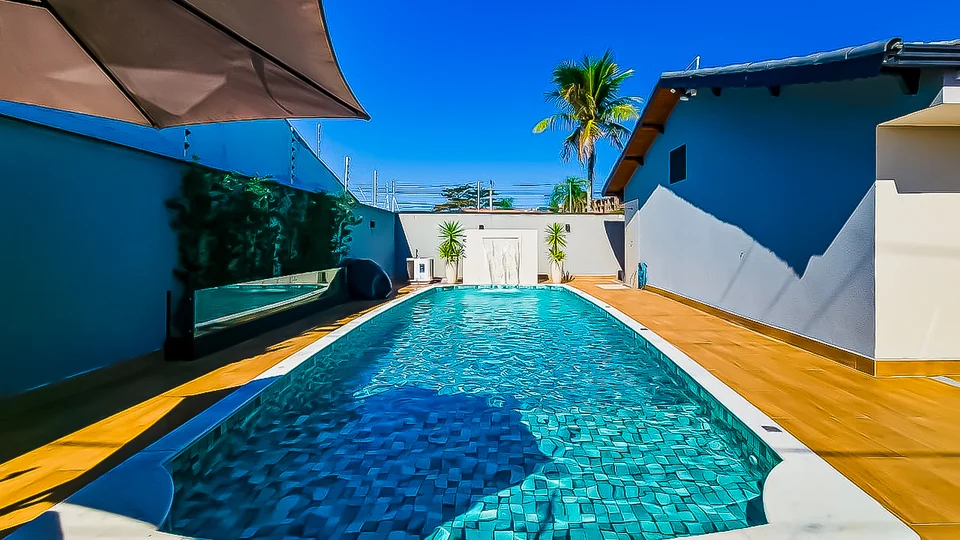 Piscina no quintal com jardim vertical e palmeira ao fundo, casa alto padrão Itanhaém